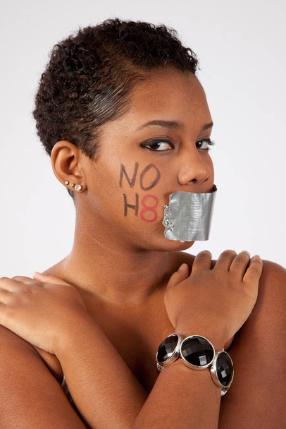 Csinos fekete nő, "NEM H8" felirattal az arcán és a szája be van ragasztva. - Fotó, kép