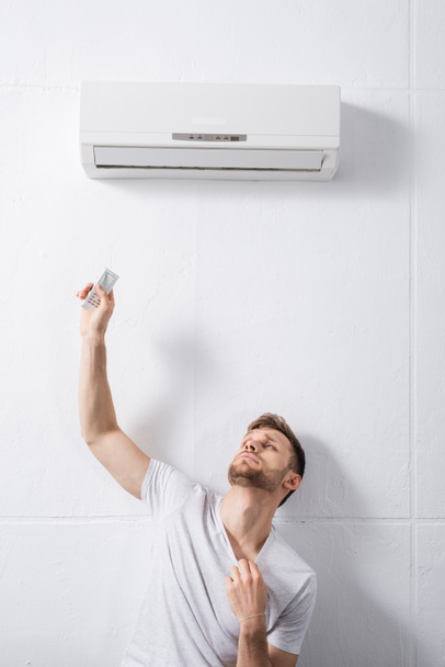 sad man feeling uncomfortable with broken air conditioner at home during summer heat  - Photo, Image