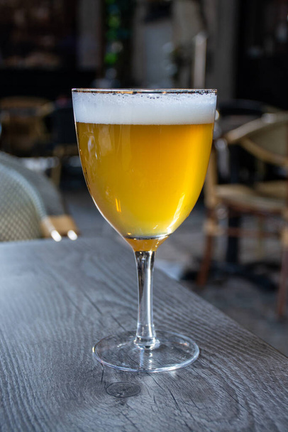 Famosa cerveza belga servida al aire libre en un pequeño café antiguo en un vaso de cerveza belga especial bajo la luz del sol
 - Foto, Imagen