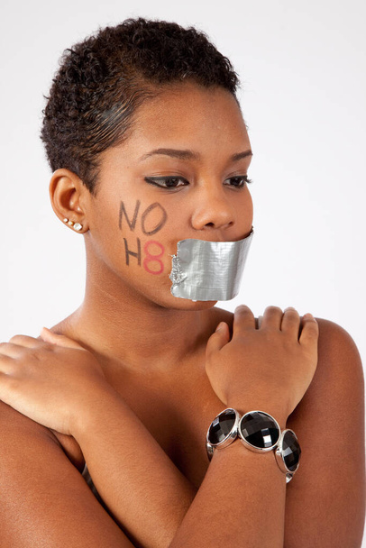 Mujer negra bonita con "NO H8" en la mejilla y la boca cerrada con cinta adhesiva
 - Foto, imagen