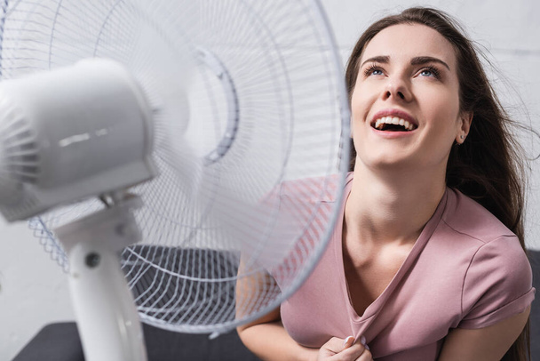 mujer emocionada sentirse cómoda con ventilador eléctrico en casa durante el calor del verano
 - Foto, Imagen