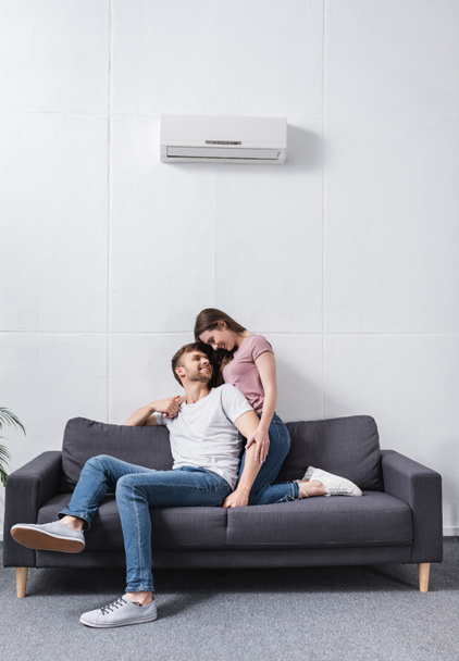 happy girlfriend and boyfriend hugging at home with air conditioner - Фото, зображення