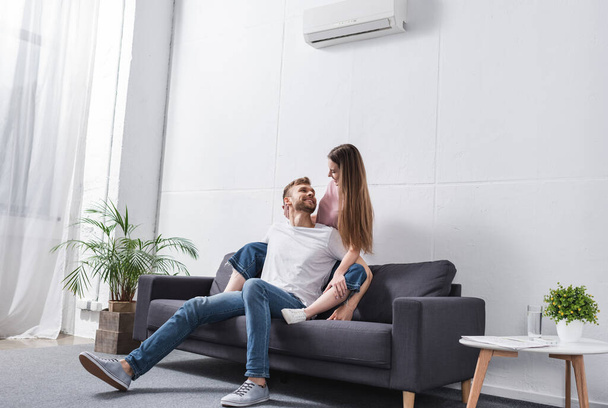 heureux couple émotionnel étreignant à la maison avec climatiseur - Photo, image