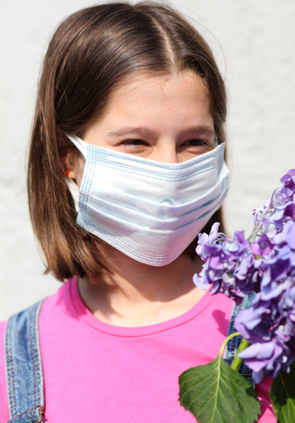 little girl with mask for protection against Covid-19 and hydrangea flowers - Photo, Image