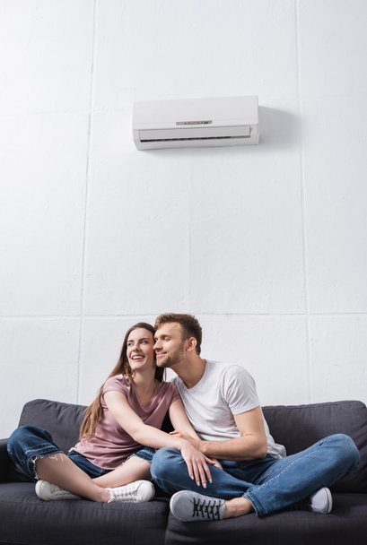 hymyilevä pari halaus kotona ilmastointilaitteella - Valokuva, kuva