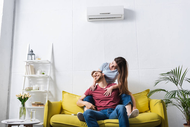 smiling couple hugging at home with air conditioner - Foto, Imagem
