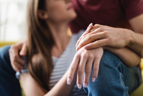 cropped view of couple hugging and holding hands at home, selective focus - Fotografie, Obrázek