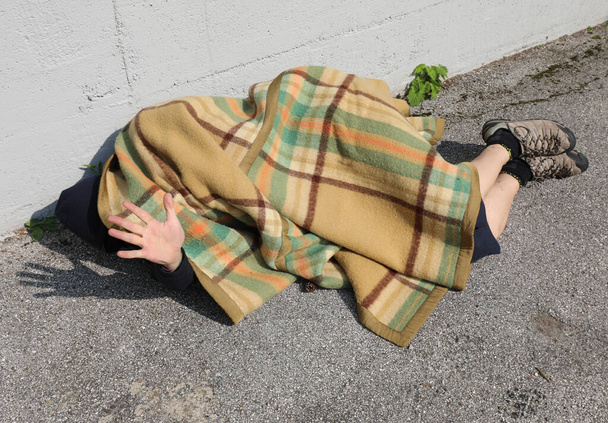 young homeless man under an old blanket and his hand raised to protect himself - Photo, Image