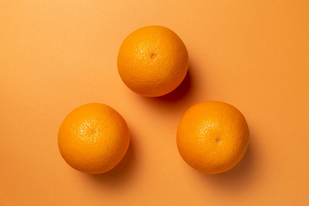 Πορτοκάλια στο πορτοκαλί φόντο. Επίπεδη. - Φωτογραφία, εικόνα