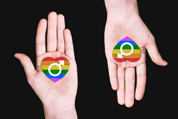 Έννοια του γάμου μεταξύ ατόμων του ίδιου φύλου. Δύο αρσενικά χέρια με καρδιές και ένα σημάδι φύλου. Σύμβολο της ΛΟΑΤ κοινότητας. Γκέι αγάπη. Μήνας υπερηφάνειας ΛΟΑΤ.. - Φωτογραφία, εικόνα