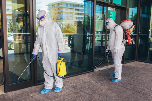 ハズマットスーツの専門労働者は、モール、パンデミック健康リスク、コロナウイルスの屋外を消毒する - 写真・画像