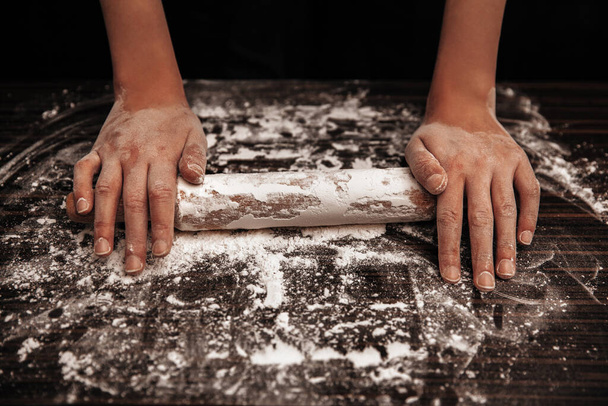 The cook holds a rolling pin on the table in flour. Close-up photo - Fotoğraf, Görsel