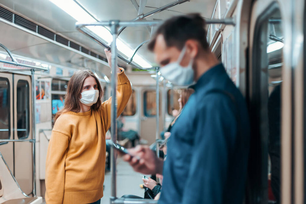 jonge vrouw met een beschermend masker staan in een metro auto. - Foto, afbeelding