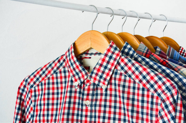close up clothes hang on shelf or clothing rack, long sleeve red and blue checkered shirt on wooden hanger over white background, copy space - Foto, immagini