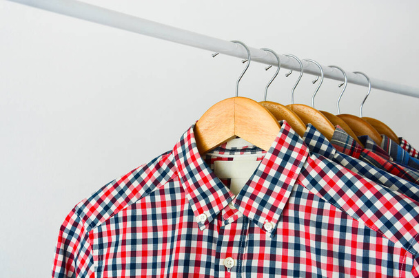 close up clothes hang on shelf or clothing rack, long sleeve red and blue checkered shirt on wooden hanger over white background, copy space - Photo, Image