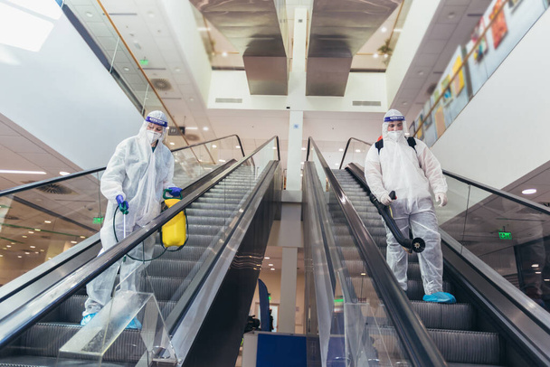 Tehlikeli madde giysileri içinde profesyonel işçiler alışveriş merkezinin iç kısımlarını dezenfekte ediyor, salgın hastalık riski, koronavirüs... - Fotoğraf, Görsel