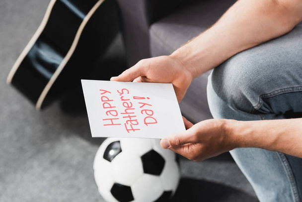 recortado vista de hombre sosteniendo feliz padre día tarjeta cerca de pelota de fútbol
 - Foto, Imagen