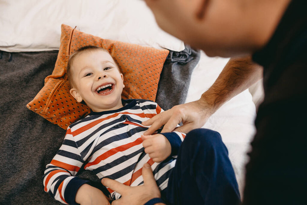 Caucasico padre e figlio divertirsi sul divano insieme durante il fine settimana ridendo felice di fotocamera
 - Foto, immagini