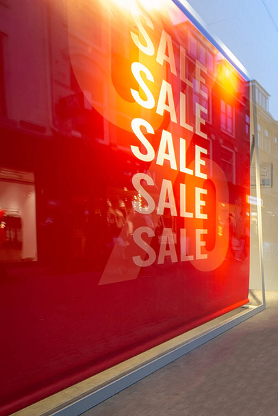 Schaufensterwerbung für den Verkauf mit einer großen roten Verkaufstafel vor dem Geschäft zur Straße in der Innenstadt - Foto, Bild