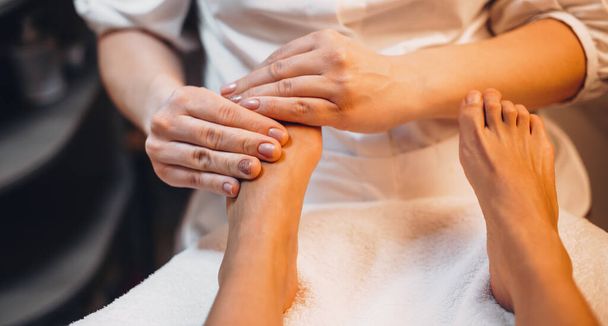 blank vrouw het hebben van een massage voor haar benen en vingers liggend op de bank in een spa centrum - Foto, afbeelding