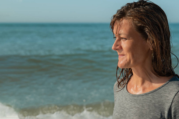 Портрет жінки в профілі дивиться на море і посміхається, море
 - Фото, зображення