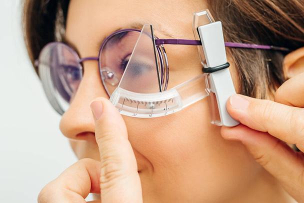 ophthalmologist measures rim of glasses with special tool - Foto, imagen