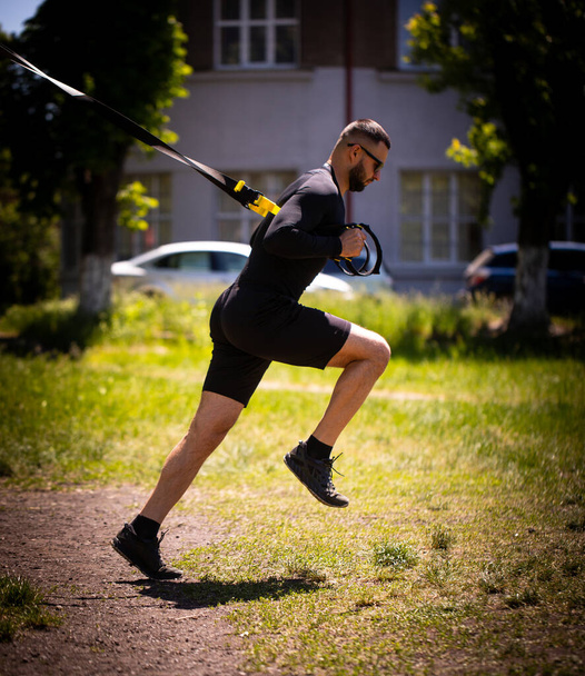 One caucasian man exercising suspension training trx on the park. - Photo, Image