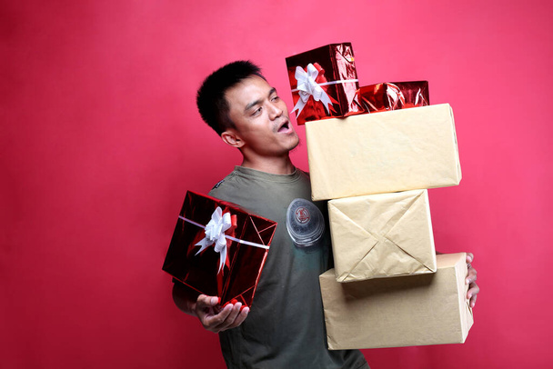 muž dává dárkové krabice na červeném pozadí. Yogyakarta indonézie. prosinec 14, 2019 - Fotografie, Obrázek