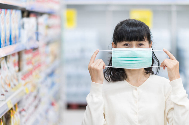 Азиатская женщина носит медицинскую маску для лица в супермаркете для предотвращения пыли распространение микробов и бактерий и избежать инфекций коронный вирус. Концепция гигиены - Фото, изображение