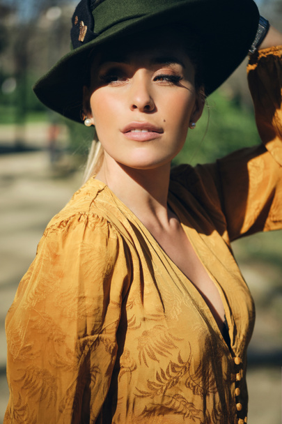 Portret van jonge prachtige vrouw met hoed op en zelfverzekerd wegkijkend buiten - Foto, afbeelding