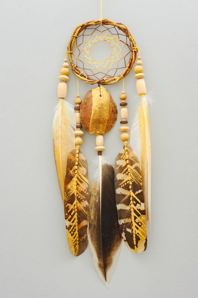Closeup details modern dreamcatcher with painted golden feathers on gray background - Photo, Image