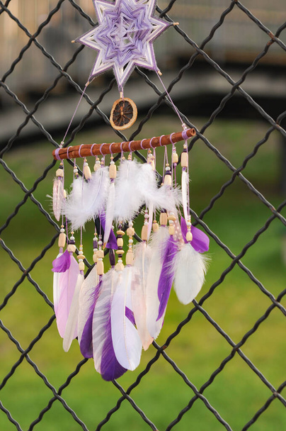 Nahaufnahme moderner Traumfänger mit lila Federn im Freien - Foto, Bild