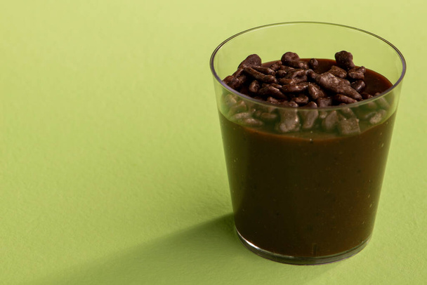 acrylic cup with brigadeiro and chocolate sprinkles on green background. - Photo, Image