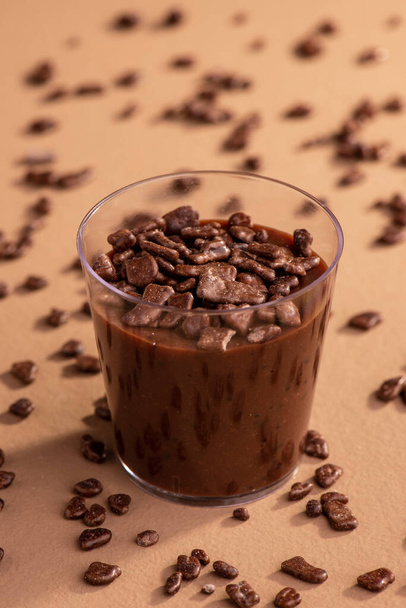 ακρυλικό κύπελλο με brigadeiro και σοκολάτα ψεκάζει σε καφέ φόντο. - Φωτογραφία, εικόνα