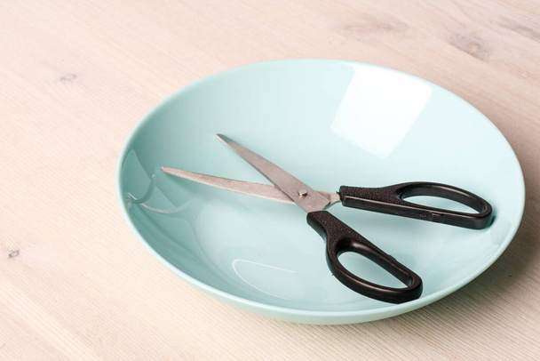 a ceramic plate in which there are scissors with plastic handles. unexpected set - Photo, Image