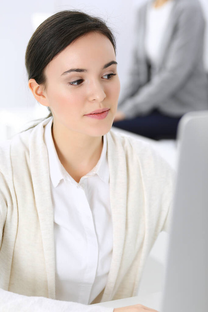 Business woman working with computer in office, female colleague at background. Headshot of Lawyer or accountant at work while sitting at the desk - Φωτογραφία, εικόνα