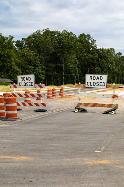 Znaki drogowe zamknięte na barykadach drogowych, pomarańczowe i białe lufy odblaskowe, przestrzeń do kopiowania asfaltu, aspekt pionowy - Zdjęcie, obraz
