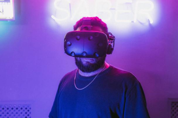 The guy is sitting in virtual reality. Neon retro style. The photo shows the effect of grain, noise. - Zdjęcie, obraz