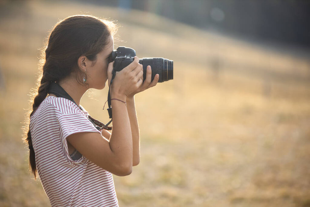 Menina caucasiana no perfil tirar fotos com uma câmera no campo
 - Foto, Imagem