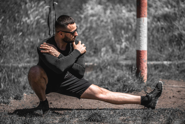 Young man is stretching before jogging. Fitness and lifestyle concept. Young man practicing yoga fitness exercise outdoor. Meditation and relaxation. - Photo, Image
