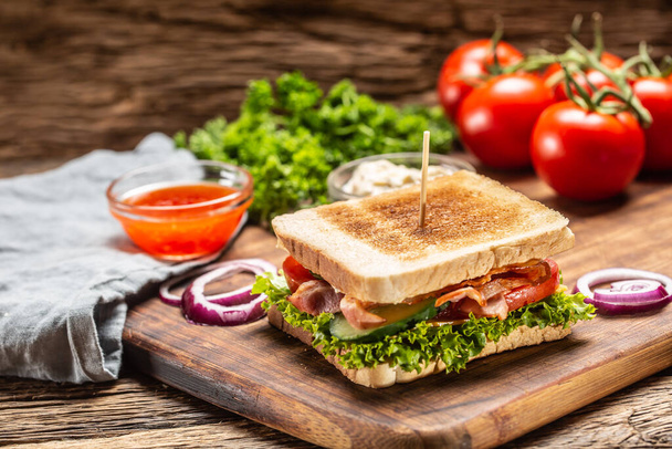BLT sandwich on a cutting board next to sweet chilli sauce and fresh vegetables - Foto, Bild