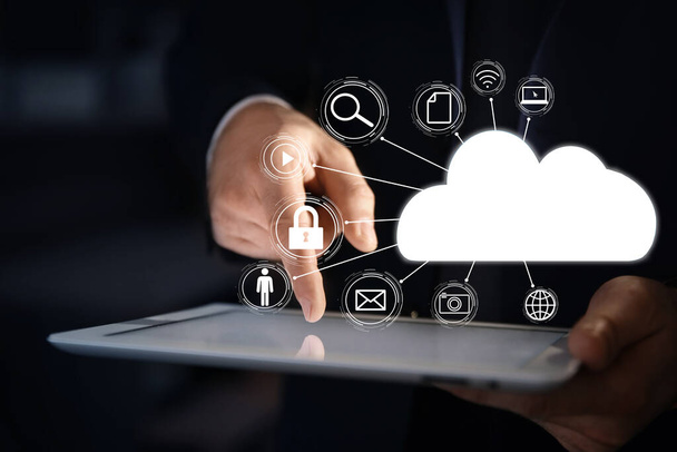 Cloud computing and storage concept. Businessman using tablet on dark background, closeup - Photo, Image