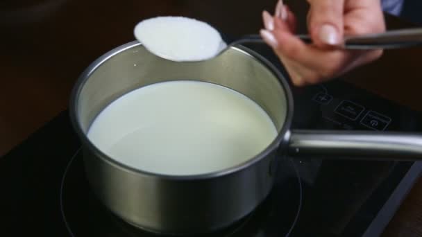 cámara lenta de la mano de la mujer por cuchara vierte azúcar en una cacerola de metal con leche
 - Imágenes, Vídeo