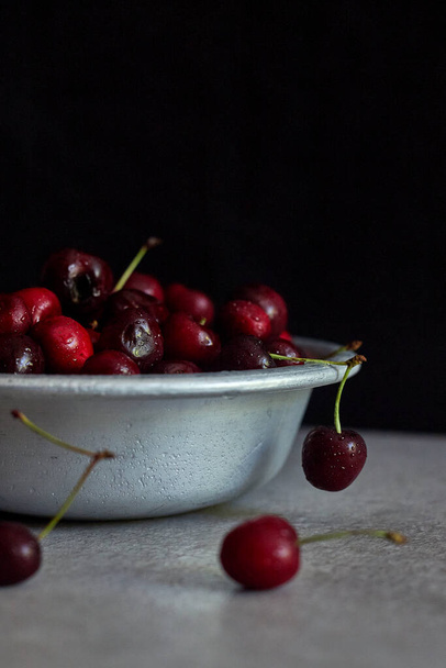 Cherry berries in a copper mug, spray on the background. - Фото, зображення