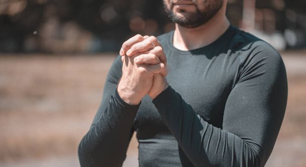 Ο άνθρωπος κάνει ασκήσεις τεντώματος χεριών για να ζεστάνει τους μυς του πριν αρχίσει προπόνηση. - Φωτογραφία, εικόνα