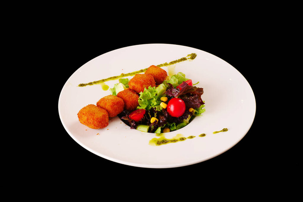 Cheese croquettes served with lettuce, tomatoes. Black background - Photo, Image