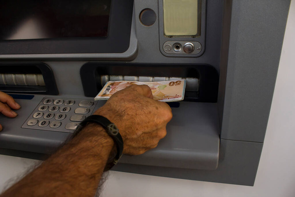 Mão de homem adulto usando máquina bancária ATM com dinheiro turco
 - Foto, Imagem