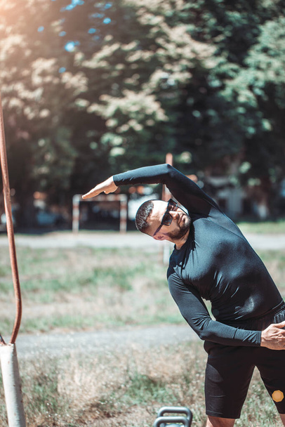 Young athlete man streching in the park outdoor. Male runner warm up ready for jogging on the road outside. Fitness walking and exercise on footpath in morning. - Fotoğraf, Görsel