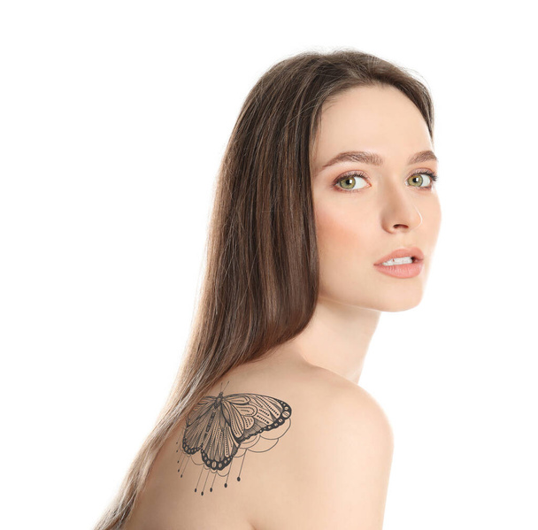Young woman with beautiful tattoo of butterfly on her body against white background - Фото, изображение
