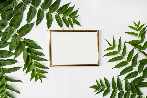 Composition moderne élégante. Cadre vide doré et feuilles tropicales vertes sur fond blanc. Pose plate. Maquette - Photo, image